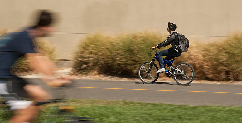 A bicyclist riding fast along a path