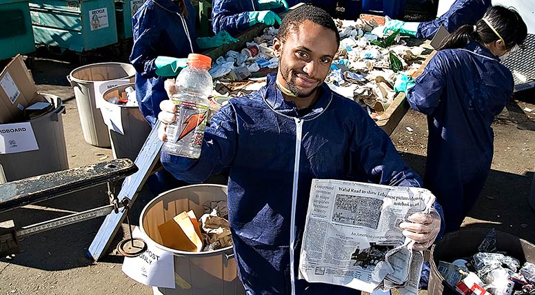 Man holding recyclable materials in an area where people are sorting
