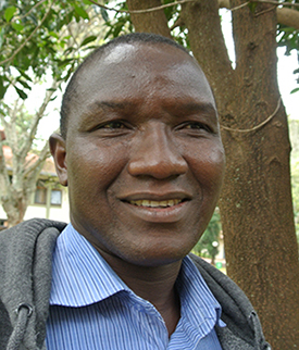 African man in gray sweatshirt over a light blue shirt.