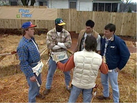 A circle of men in construction clothes in a back yard