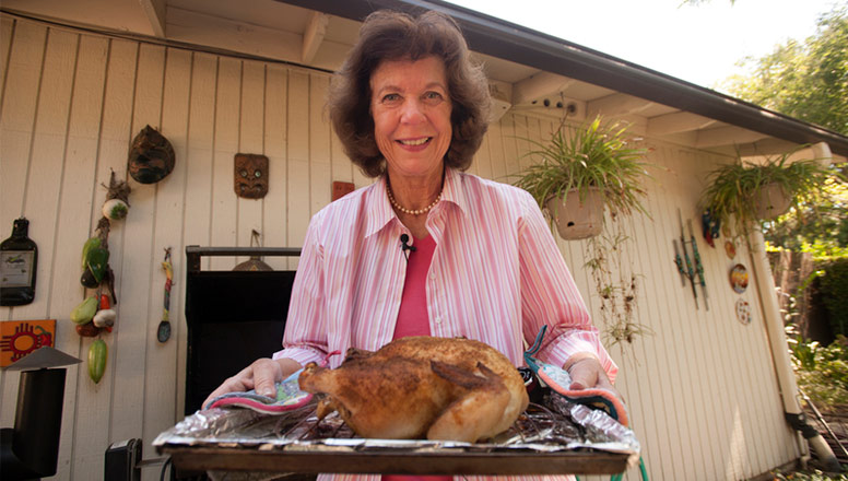 Woman holding a tray with a cooked chicken