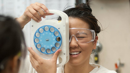 Rose Hong Truong looking through her VisionFinder tool at a woman in the foreground, demonstrating how it works