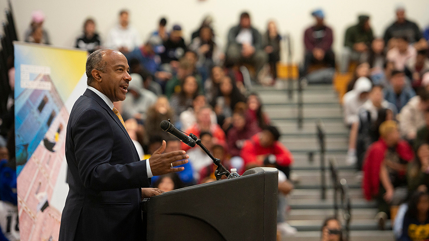 Chancellor May at a podium with students in the background