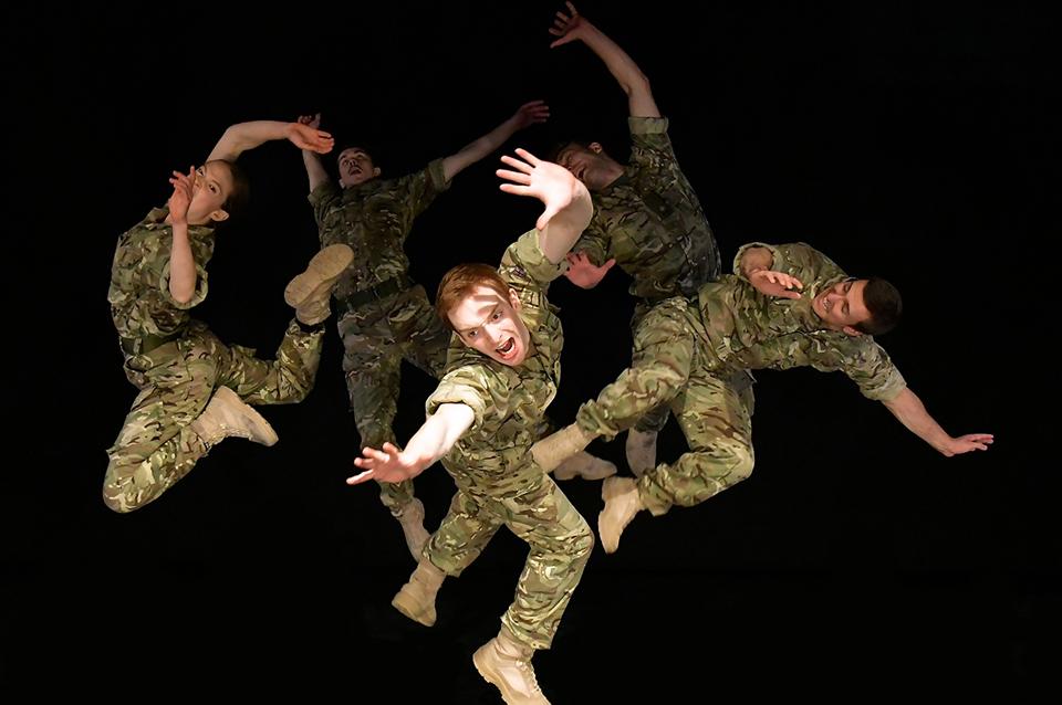 Five dancers dressed in army camouflage caught in various positions suepended in the air.