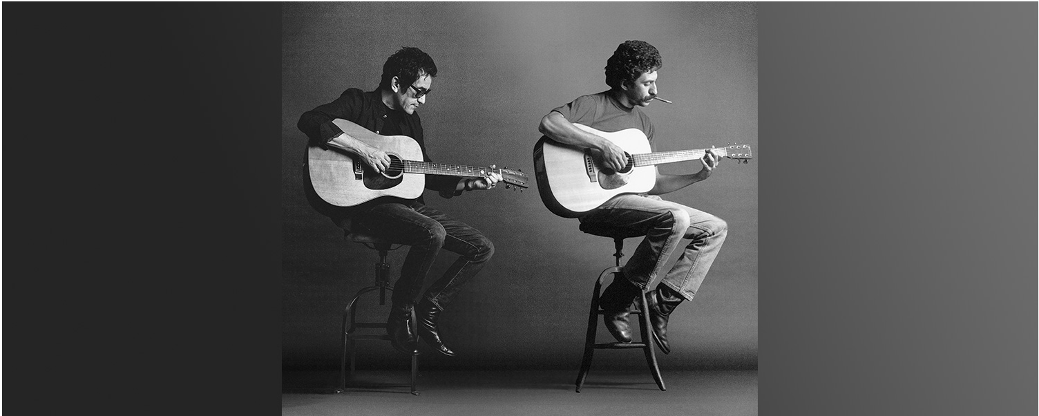 Jim and A.J. Crocer sitting on stools playing guitars in the same position, making it appear like they are on the same stage at the same time. 