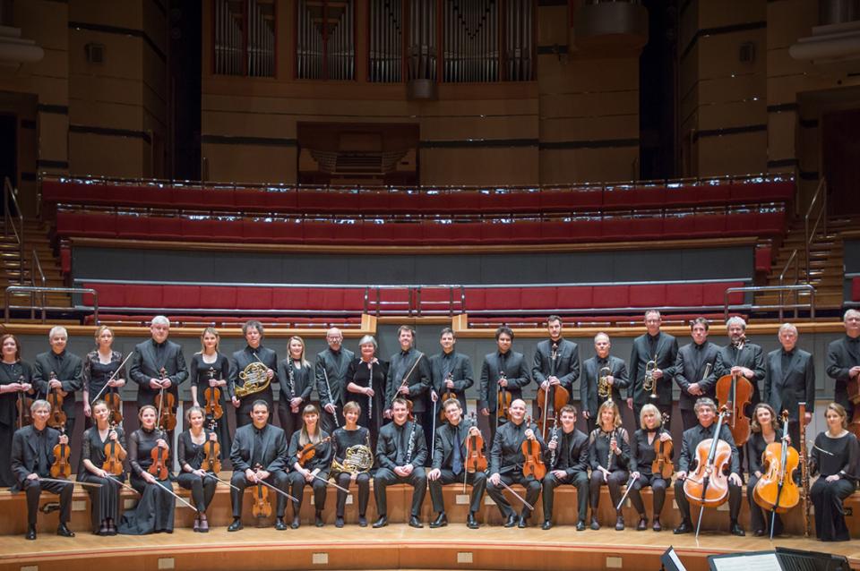 The Academy of St. Martin in the Fields orchestra posing on stage.