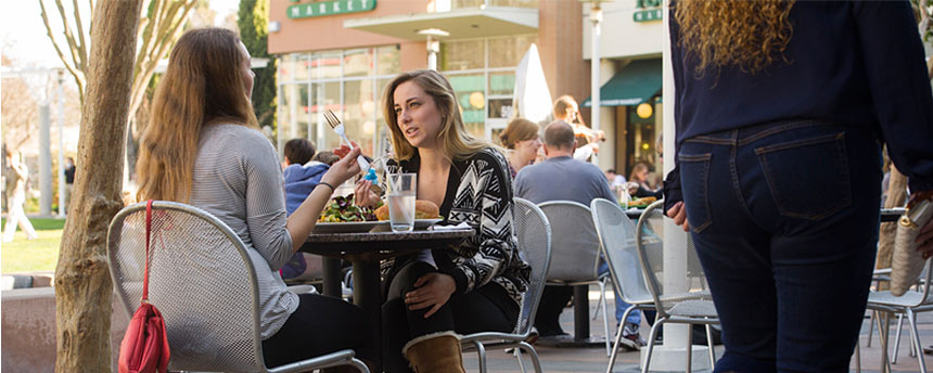 Two women eating at table outdoors