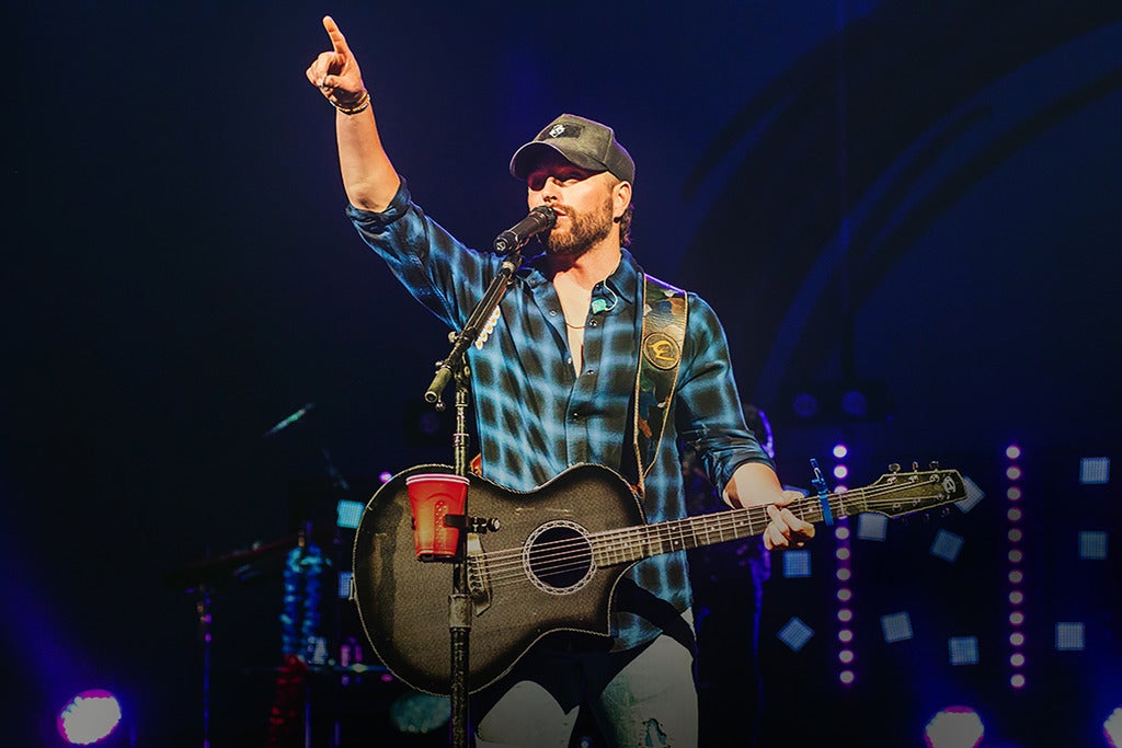 Chris Lane singing on stage holding a finger in the air.