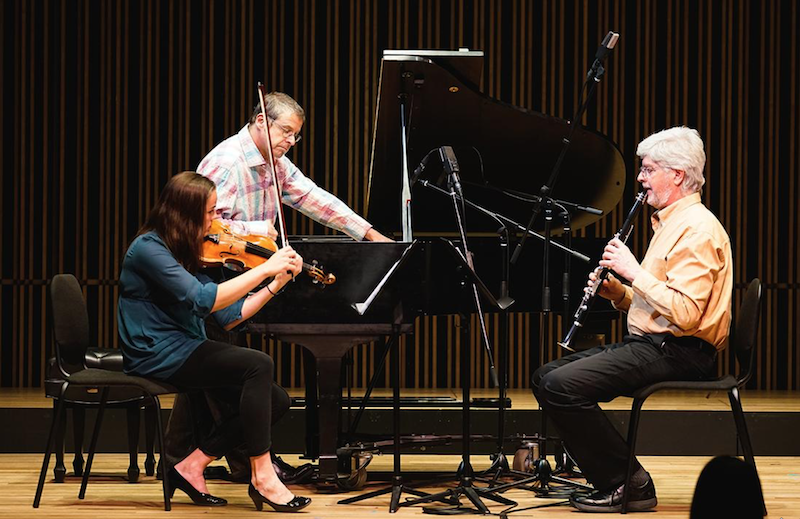 Three members of the ensemble performing on stage.