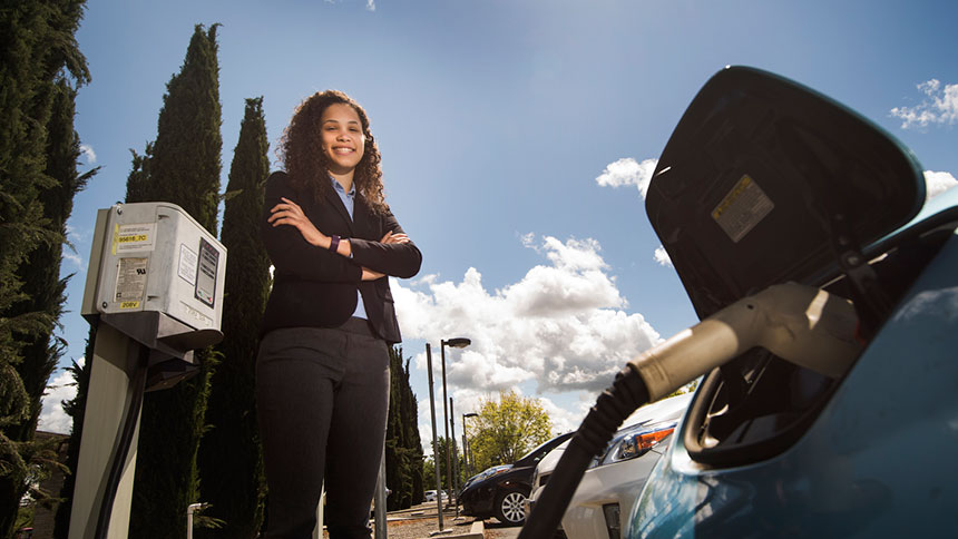 Woman standing by charging station for electric car