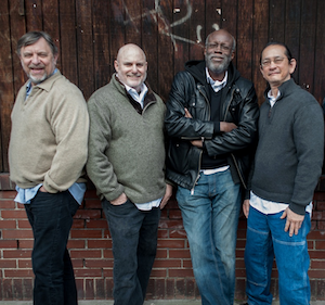 Members of the quartet standing in front of a wall.