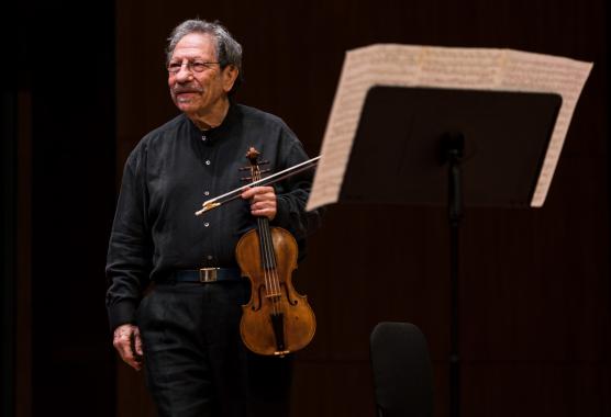 Michael Sand holding his violin on stage.