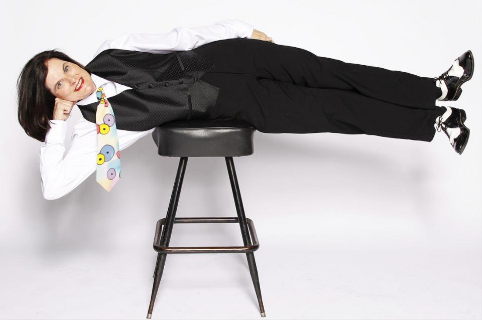 Paula Poundstone lying horizontal on a stool.