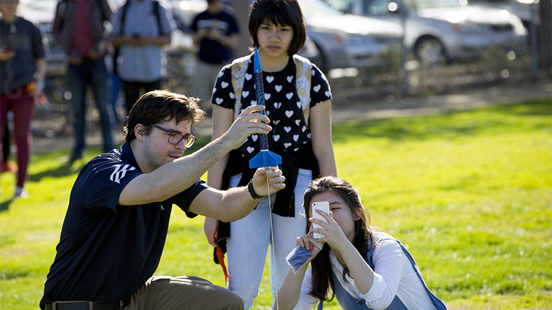 An instructor and two students prepare to launch a mall rocket