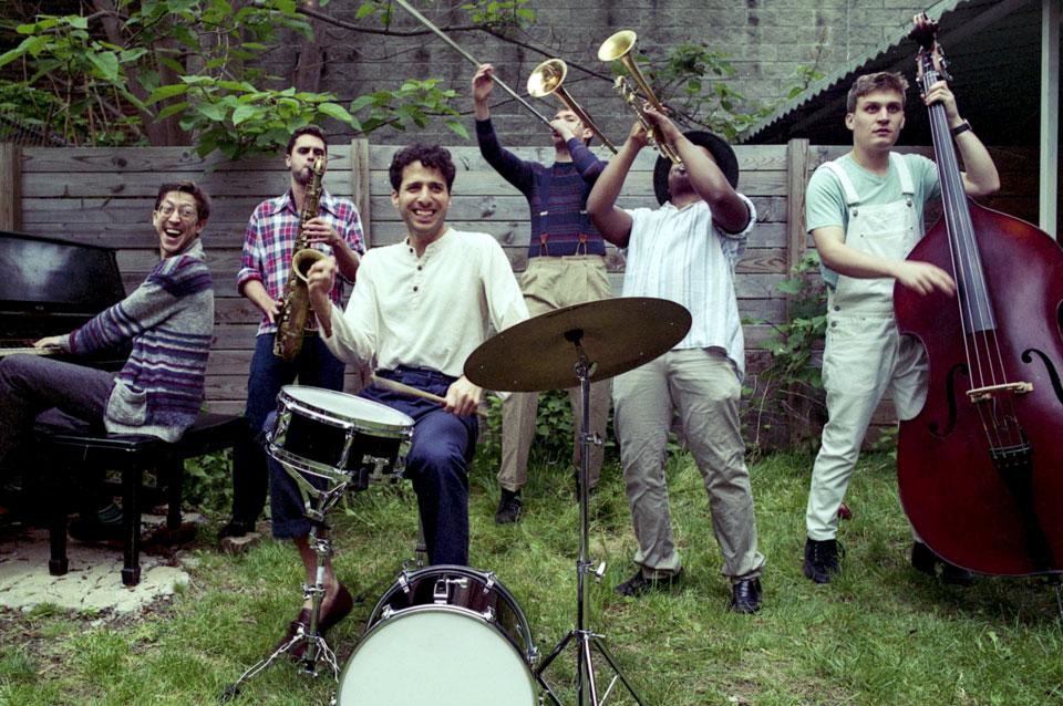 Sammy Miller and the Congregation joyfully playing their insturments in a grassy backyard.