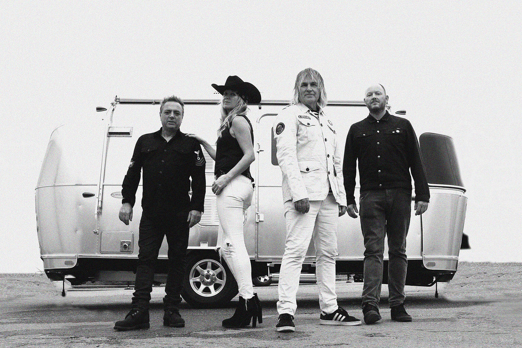 The band posing in front of a stainless steel camper.